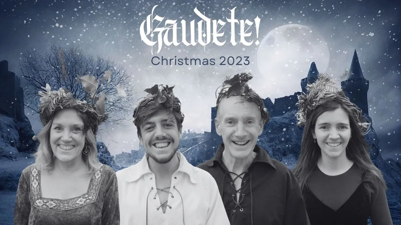 Cuatro miembros de la familia Warn, con coronas festivas, sonríen sobre un fondo nevado de temática medieval con el texto "¡Gaudete! Navidad 2023" sobre ellos. | Jacob Warn